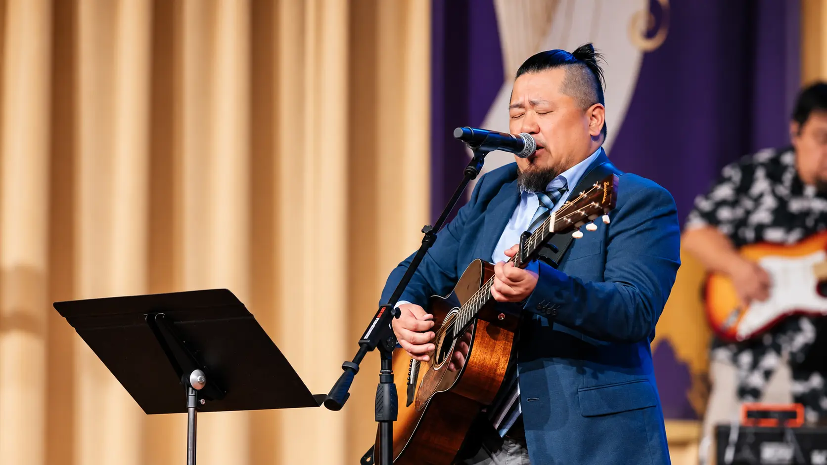 A GHAC worship leader singing and playing guitar